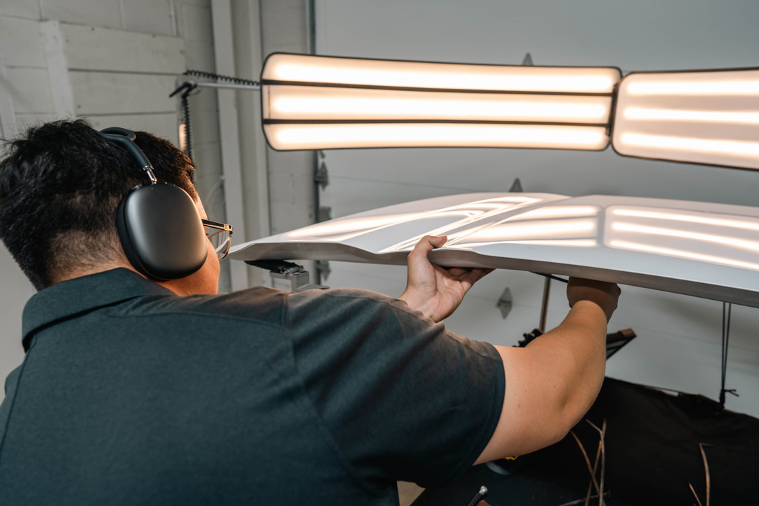Pro PDR technician working on a body-line dent under precision PDR lighting in the Houston shop