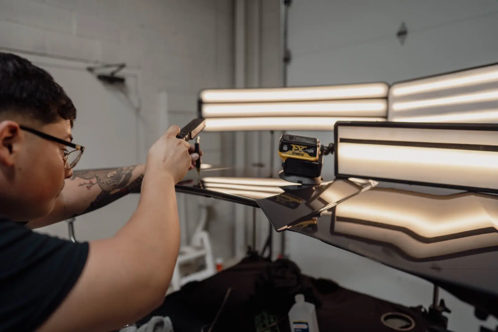 Pro PDR technician using a PDR light board to read a hood panel