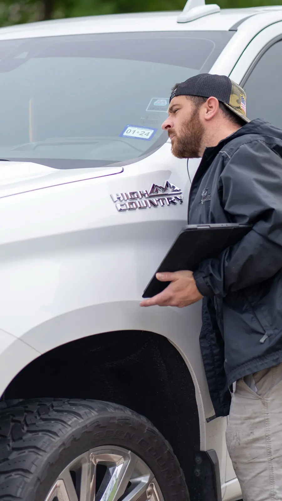 Technician inspecting hail damage on a vehicle