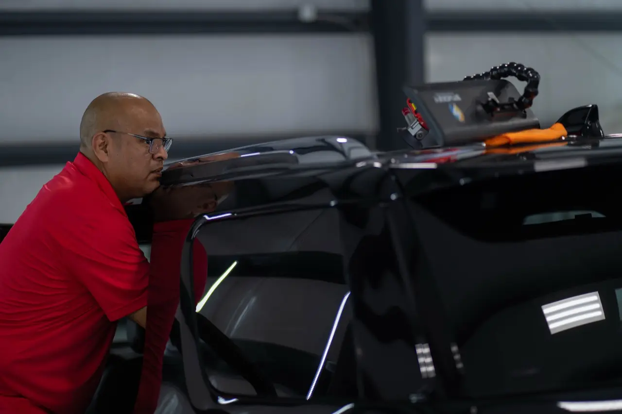 Pro PDR technician inspecting a vehicle roof at the Houston shop